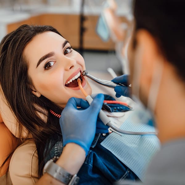 Dentist in gloves performing a comfortable dental procedure on a relaxed female patient in a modern clinic